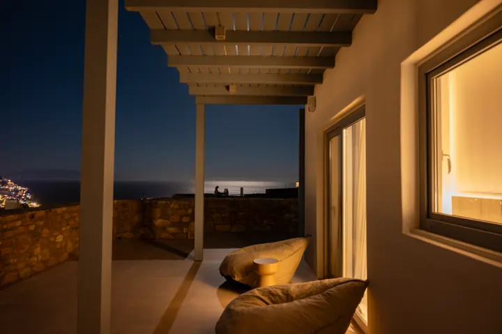 Covered sea-view terrace with cozy lounge seating at sunset