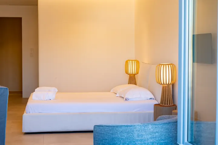 Bright minimalist bedroom with warm lighting and crisp white linens