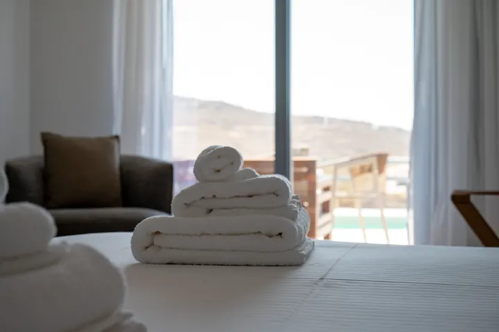 Bright bedroom with fresh towels, natural light, and a private terrace view