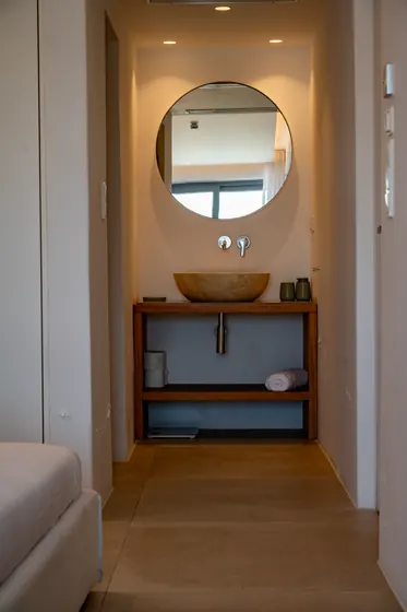 Elegant vanity nook with stone sink and round mirror lighting