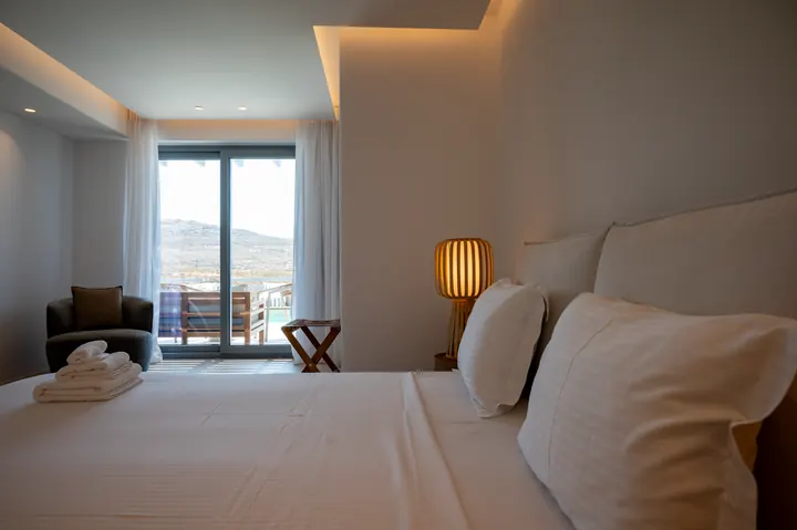 Bright modern bedroom with balcony seating and scenic hillside views