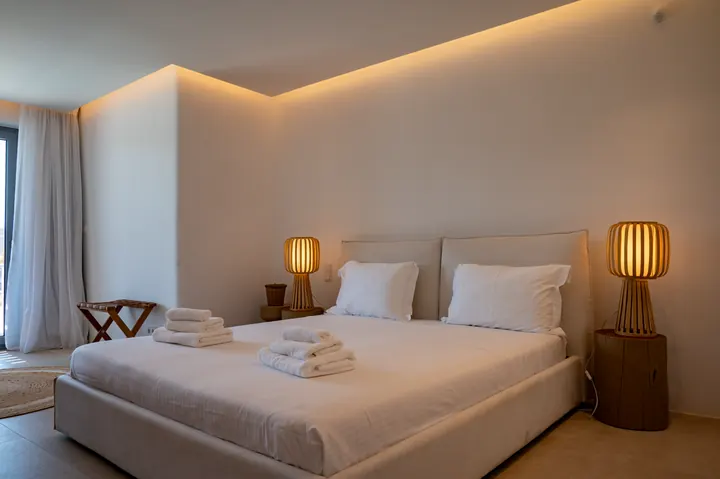 Calm minimalist bedroom with soft lighting and crisp white linens
