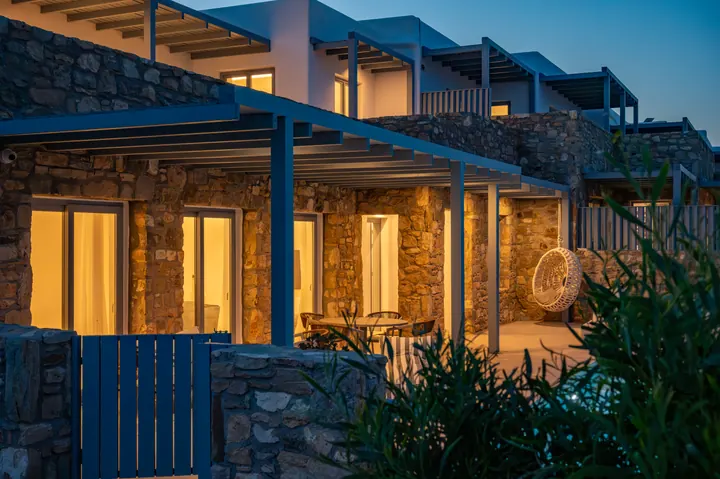 Warmly lit stone villa with covered patio and upscale evening ambiance