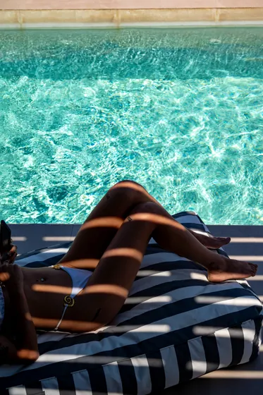 Resort-style poolside lounging with sparkling water and chic sunbed