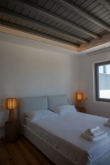 Minimalist bedroom with warm lighting and elegant exposed beam ceiling