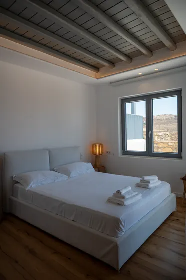 Bright minimalist bedroom with exposed beams and scenic window views