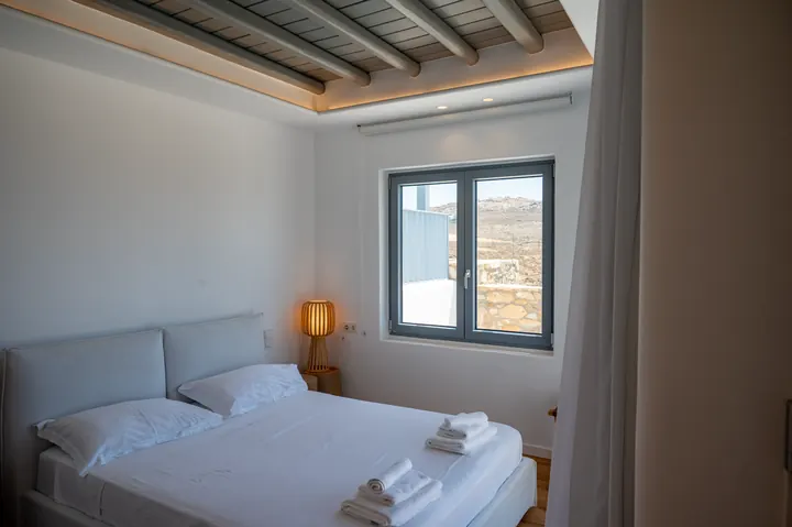 Bright minimalist bedroom with exposed beams and scenic natural light