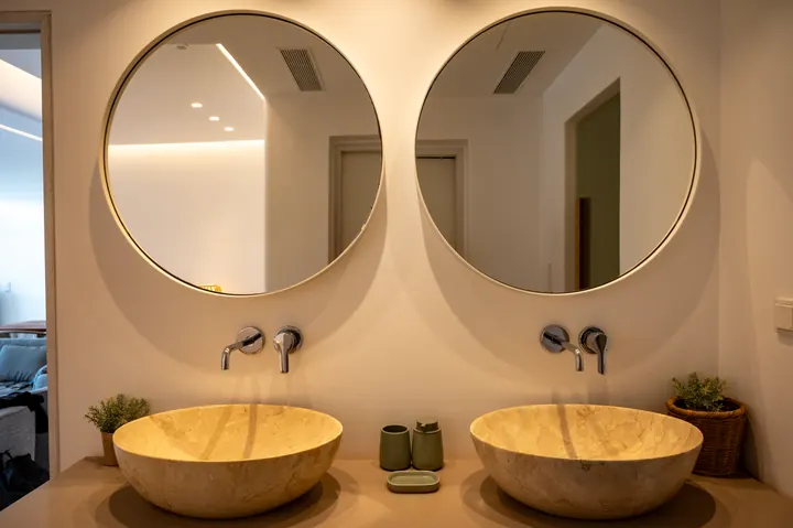 Spa-like double vanity with stone sinks and elegant round mirrors