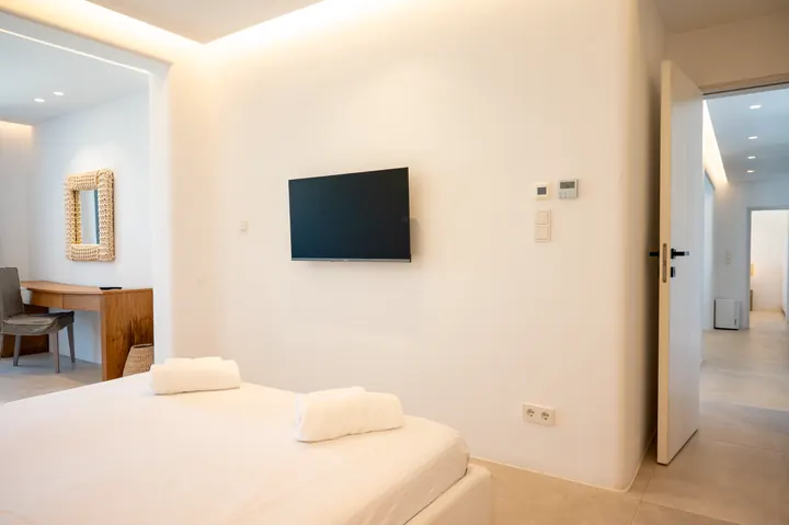 Bright modern bedroom with TV, soft lighting, and a sleek minimalist design