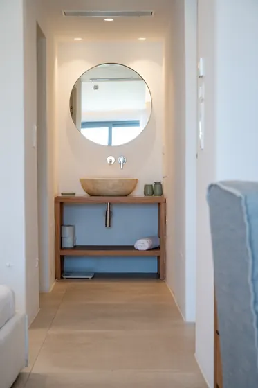 Spa-like vanity with stone sink, round mirror, and warm modern design