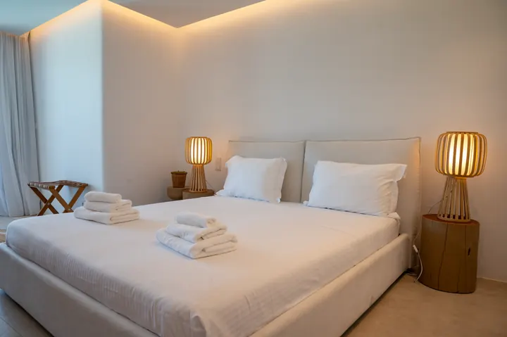 Serene king bedroom with warm lighting and crisp hotel-style linens