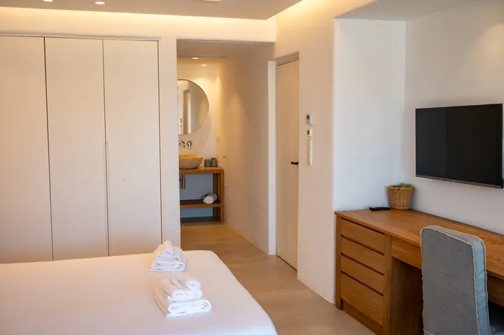 Bright modern bedroom with built-in storage, desk, and wall-mounted TV