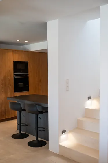 Modern designer kitchen with breakfast bar and illuminated staircase