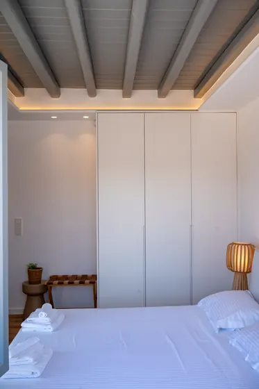 Minimalist bedroom with exposed beams and soft ambient lighting