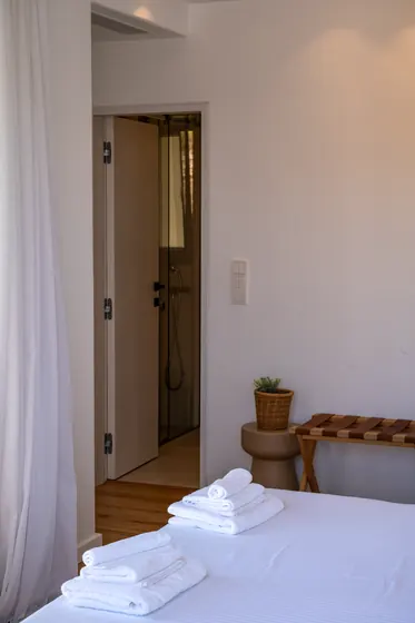 Bright minimalist bedroom with en-suite shower and crisp white linens