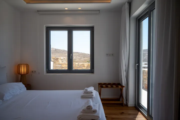 Bright modern bedroom with hillside views and private balcony access