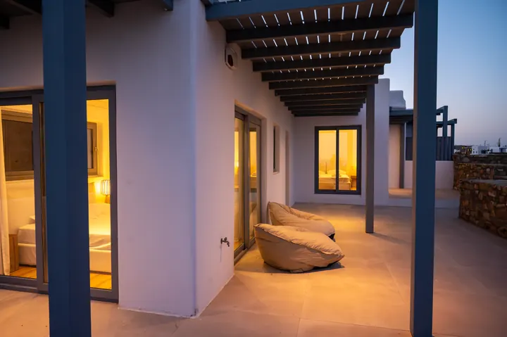 Modern covered terrace with cozy lounge seating and warm evening ambiance
