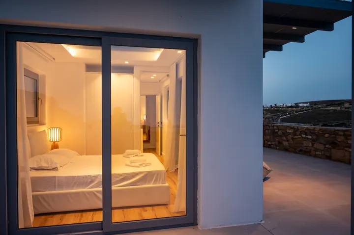 Modern bedroom with terrace access and warm evening ambiance