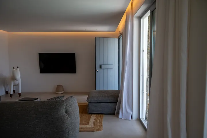 Minimalist lounge with soft lighting, TV, and bright patio doors