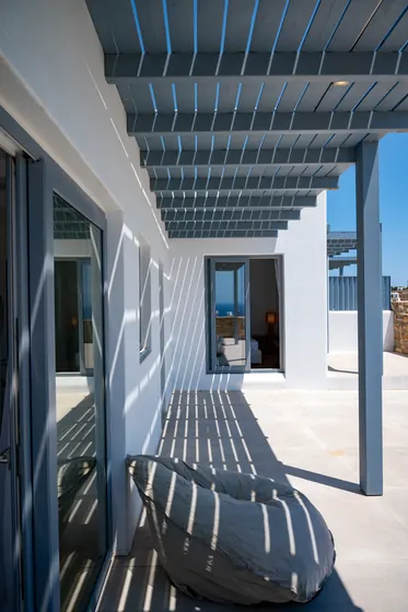 Sun-dappled terrace with pergola shade and serene sea-view glimpses