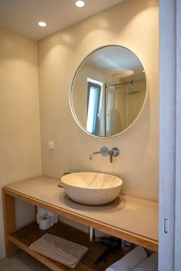 Spa-like bathroom with vessel sink, round mirror, and warm modern design