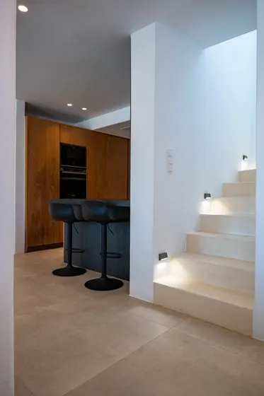 Modern kitchen nook with breakfast bar and softly lit staircase