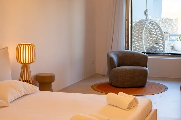 Bright minimalist bedroom with cozy lounge chair and natural light