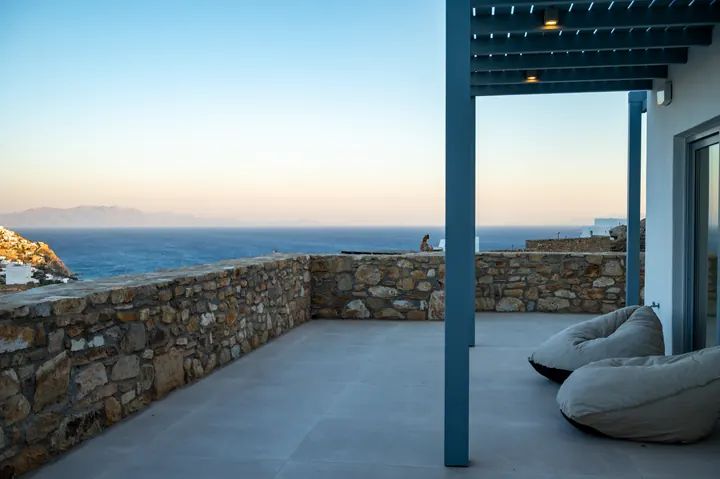 Covered sea-view terrace with cozy lounge seating and sunset vistas