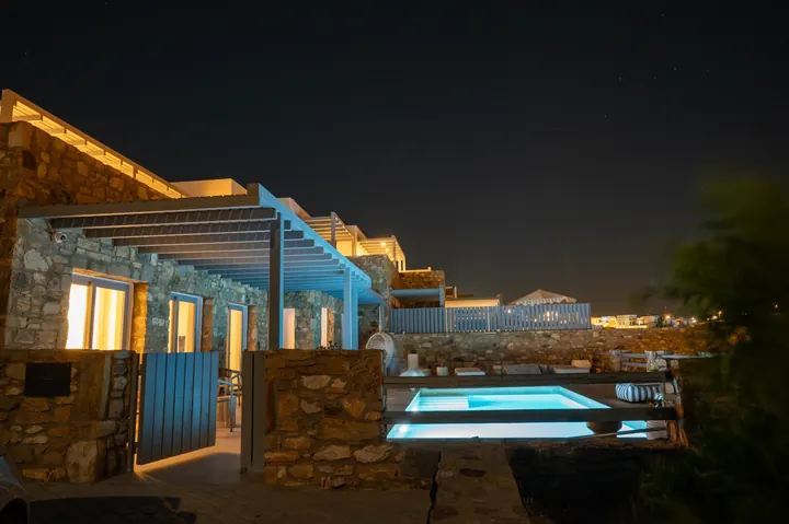 Stone villa with glowing private pool and inviting outdoor lounge at night
