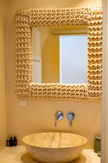 Spa-like bathroom with stone vessel sink and statement woven mirror