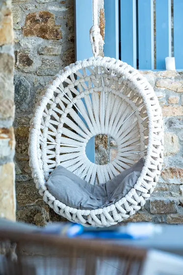 Cozy woven hanging chair with rustic stone and breezy coastal charm