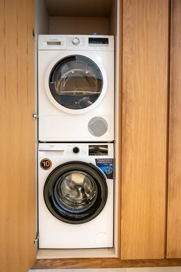 In-unit stacked washer and dryer tucked neatly behind wood cabinetry